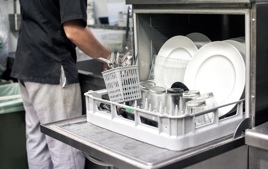 Pratos brancos limpos em uma cozinha de restaurante; Cozinha industrial; louças limpas; homem lavando louça