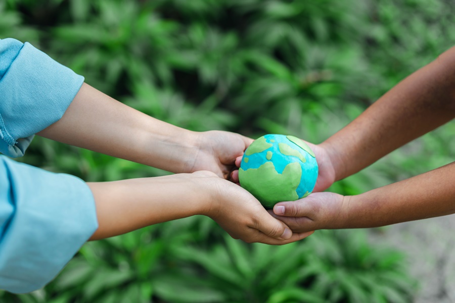 duas pessoas segurando o conceito de proteção ambiental, sobre fundo verde, representando a importancia do mercado de carbono
