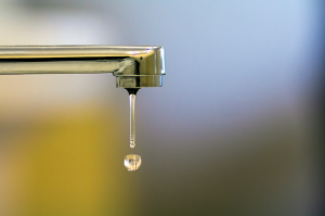 Close-up da torneira com gota de água virada no banheiro moderno, água acabando