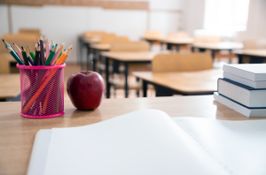 De volta ao conceito de escola. Acessórios e livros, sala de aula desfocada ao fundo, maçã para professor