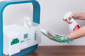 self cleaning da rl higiene, ao lado da ferramenta uma mão com luvas usando um produto de limpeza