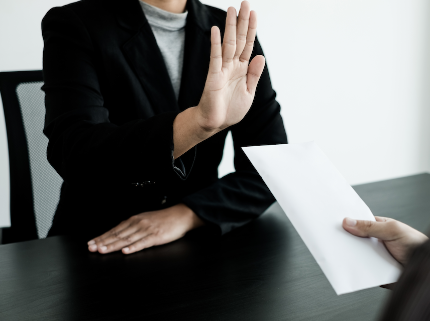homem com integridade recusa uma proposta de corrupção fazendo sinal de negativa com as mãos