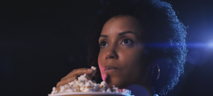 mulher na sala de cinema assistindo um filme enquanto come pipoca