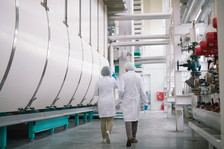 dois funcionarios de uma industria trabalhando, corredores limpos. discussões sobre limpeza profissional foram foco no fórum de industrias