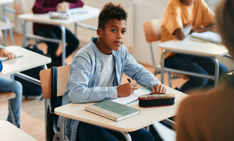 Estudante do ensino fundamental e seus colegas durante uma aula na escola